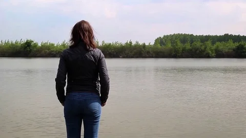 Woman standing on the bank of the river and looking into the distance Stock Footage