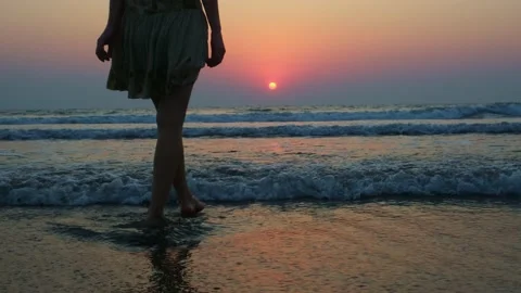 Woman standing on the beach at sunset. Stockbeeldmateriaal 234106976