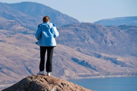 A woman standing on cliff's edge over a fantastic mountain view Stock Photos