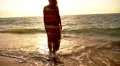 Woman Standing on Coast in Sea and Looking at Sunset. Slow Motion. HD Footage