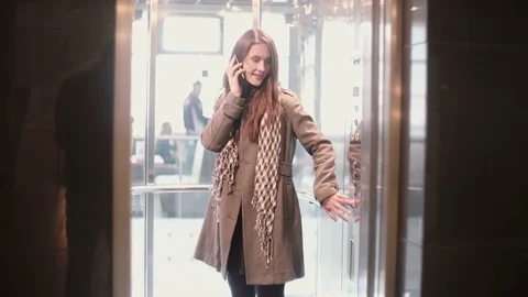 Woman standing in the elevator and talking on the smartphone. Female press the Stock Footage 73148060