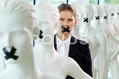 A woman standing in line of mannequins with taped mouth Stock Photos