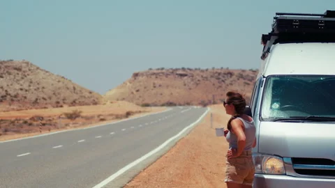 Woman standing next to van on empty road in desert Stock-Footage 326352064