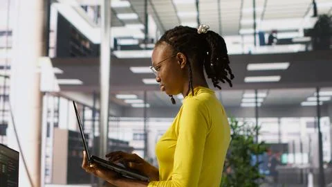 Woman standing in office, fixing coding issues using laptop Stock Photos