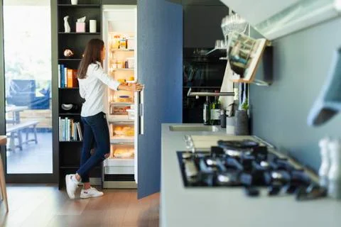 Woman standing at open refrigerator in kitchen Stock Photos