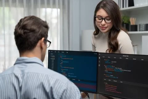 Woman standing opposite to man programmer working on desk to discuss. Postulate. Stock Photos