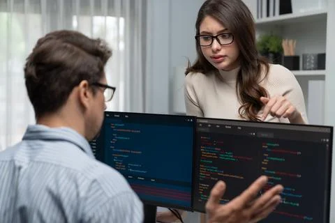 Woman standing opposite to man programmer working on desk to discuss. Postulate. Stock Photos