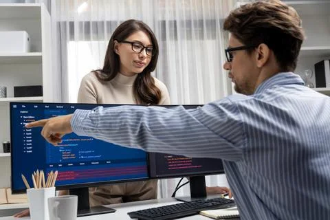 Woman standing opposite to man programmer working on desk to discuss. Postulate. Stock Photos