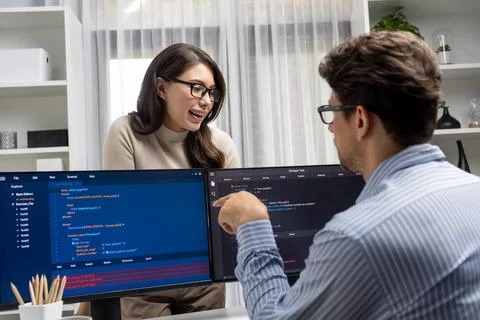 Woman standing opposite to man programmer working on desk to discuss. Postulate. Stock Photos