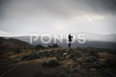 Woman standing in a prairie under a cloudy sky. Stock Photos
