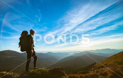 The woman standing on the rock with a picturesque sunset Stock Photos