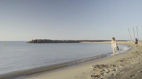 Woman standing on a sandy beach looking at the calm sea bay Stock Footage 342445966