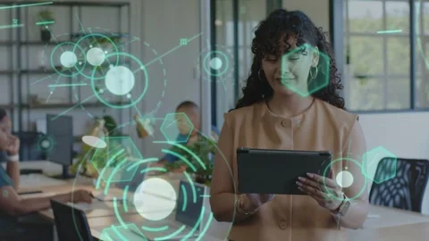 Woman standing in shared tech office tapping tablet and testing holographic UI Stock Footage 333774431
