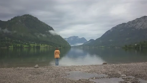Woman standing on the shore and throwing stones in water Stock Footage 132061053