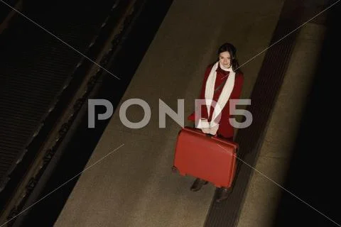 A woman standing on a station platform and holding a suitcase Stock Photos
