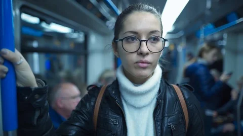 Woman standing on a subway train while holding on to a pole Stock Footage 125236095