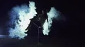 The woman standing in twine in the smoke cloud. night time, slow motion 4k or 4k+ Resolution