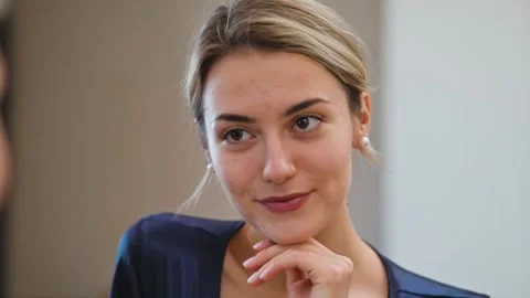 A woman stands in front of a mirror applying makeup and adjusting her hairstyle Stock Footage 337555385