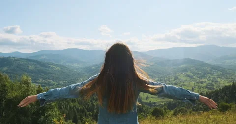 Woman stands in front of a stunning view of the mountains and the green valley Vídeo Stock 194166345