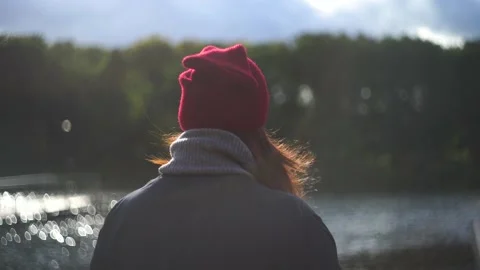 Woman stands with her back in the frame on the river bank. Warm glare of the sun Stock Footage 140959336
