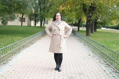 Woman stands on paved path lined with trees Фото