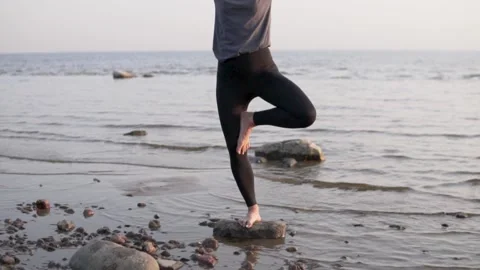 The woman stands in a pose of a tree on a stone by the sea Stock Footage 140579869