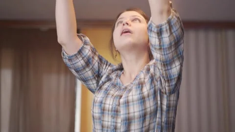 A woman stands stool changes light bulb into chandelier. Electrician woman Stock Footage 144639481