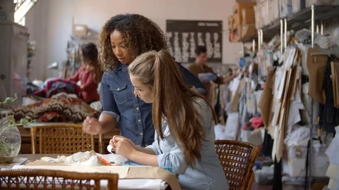 Woman stands to train an apprentice at clothes design studio Stock-Footage 72510907
