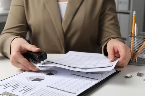 Woman stapling documents at white table indoors, closeup 写真素材