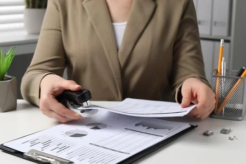 Woman stapling documents at white table indoors, closeup 写真素材