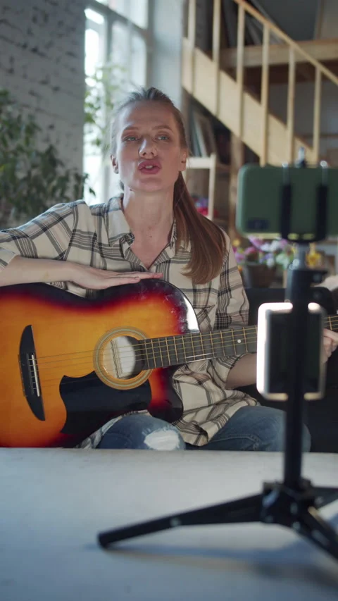 A woman starts broadcasting on her phone and tells viewers about her guitar Stock Footage 172686053