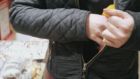 A woman steals food from a supermarket. Thief in the store. Shoplifting. Stock Footage 139782984