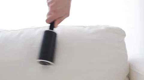 Woman with sticky roller cleaning sofa upholstery Stock Footage