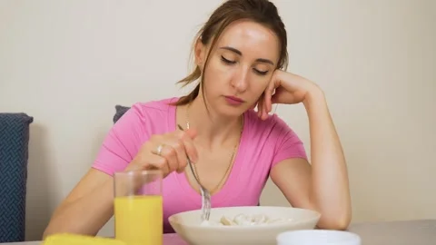 Woman stirring dumplings with fork while sitting at dining table Stock Footage 328372162