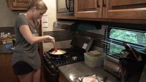 Woman Stirring Eggs for Breakfast While Camping in 5th Wheel Stock Footage 80617515