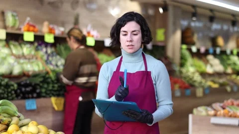 Woman store employee with folder of documents takes inventory in vegetable store Stock Footage 331306628