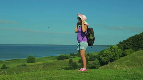 A woman in a straw hat with a backpack rises up the mountain along the path Stock Footage 93414766
