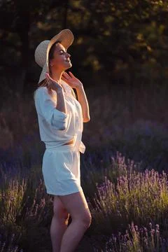A woman in a straw hat in a white suit made of light fabric in a lavender fie Stock Photos