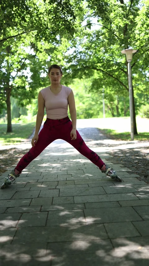 Woman stretches into a wide side split while wearing roller skates in a park Video stock 341476457