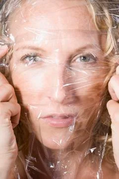 Woman stretching transparent sheet across her face Stock Photos