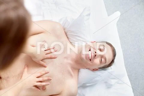 Woman stroking her happy man lying on bed, above veiw Stock Photos