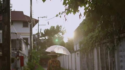 Woman strolling as the sun appears while it is still raining Stock Footage 221716913