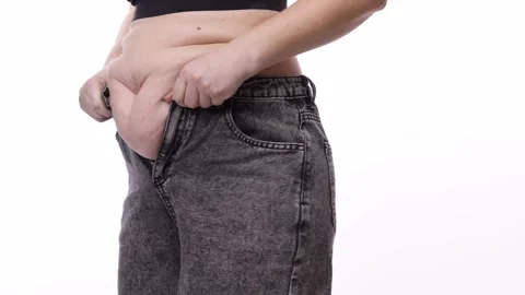 Woman struggles to fasten tight-fitting black jeans, revealing a visible Stock Footage 330073085