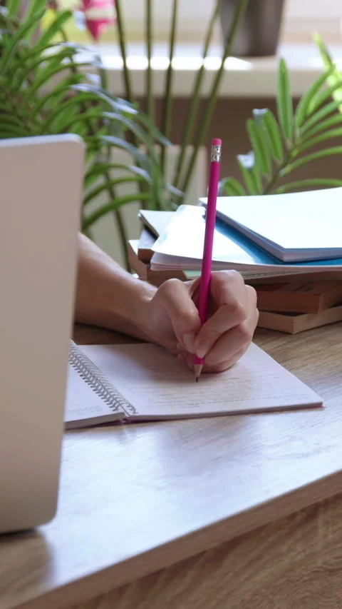 Woman student scribbles notes while reading scholarly article on laptop. Stock Footage 305407373