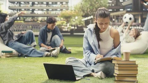 Woman student writing down notes from open book during study time Stock Photos