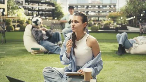 Woman student writing down notes from open book during study time Stock Photos