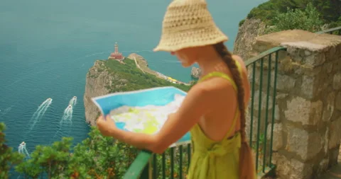 Woman studies a map above the Punta Carena lighthouse in summer Capri, Italy Stock Footage 313307490