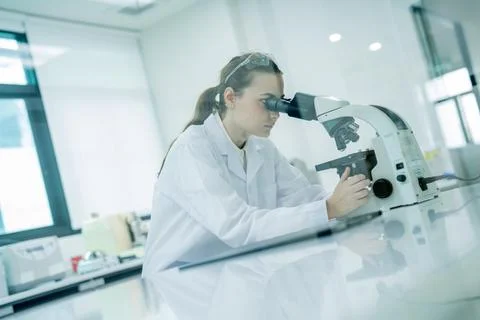 Woman studies samples with microscope in laboratory during daytime hours Stock Photos