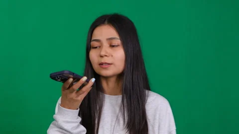 Woman in a studio using a phone app to record her voice message, demonstrating Stock Footage 263415903