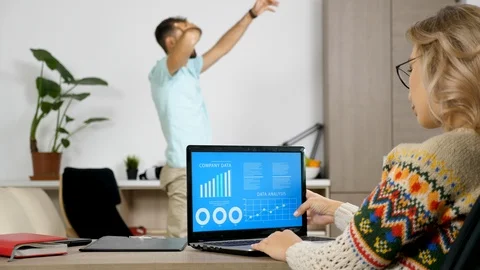 Woman studying company data analysis on animated chart while her husband is Vídeo Stock 95141122